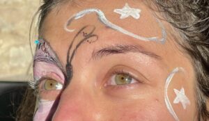 This image shows a close-up of Nazan's face, face painted! There are patterned stars and swirls, and a huge butterfly around her eye.