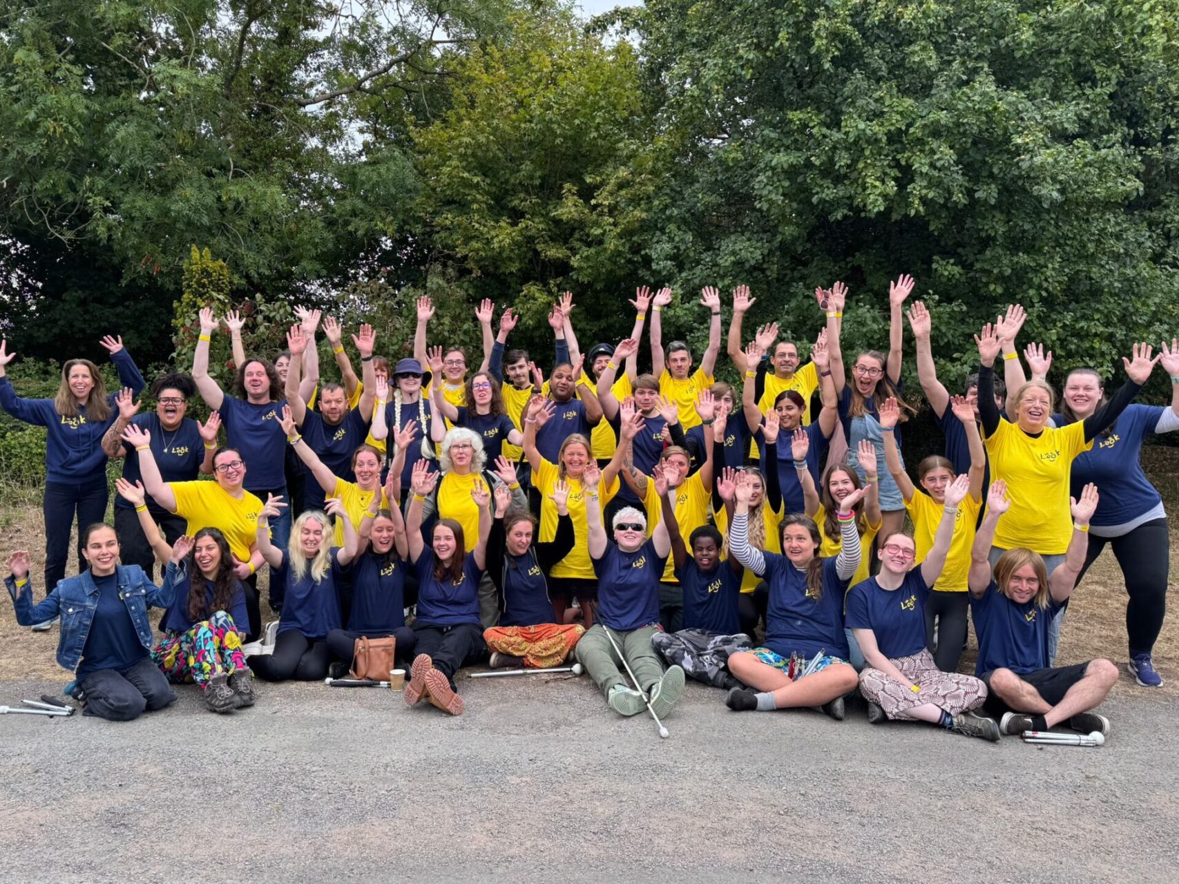 This is a group photo of the LOOK team! (Including sighted volunteers, mentors, and LOOK staff). Everyone has there hands interlaced togetehr, and up!